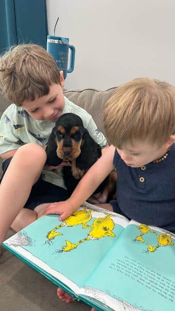 Marec and Pierce read to one of the English Cocker puppies.