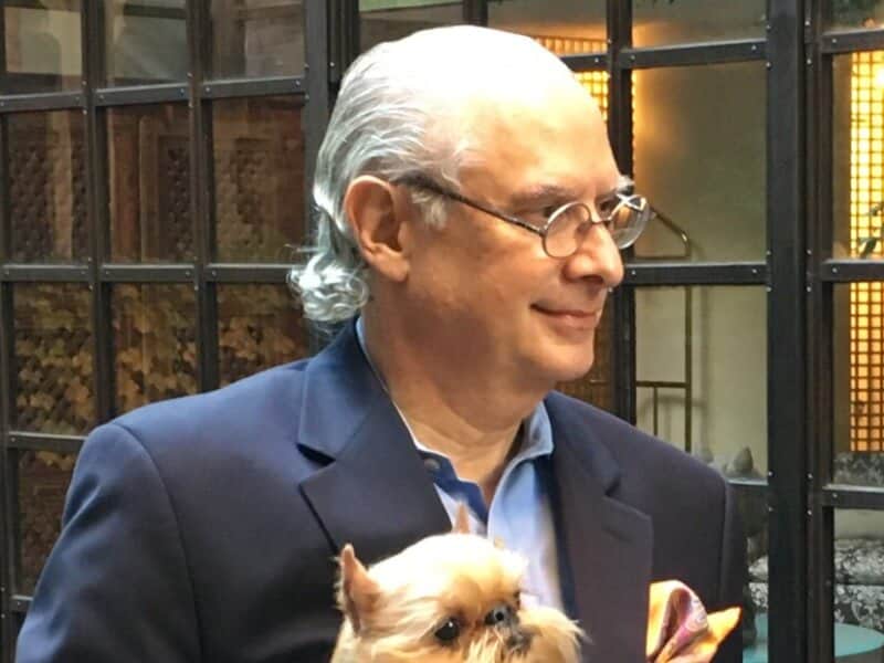 Dennis Sprung holding a small dog in his arms.