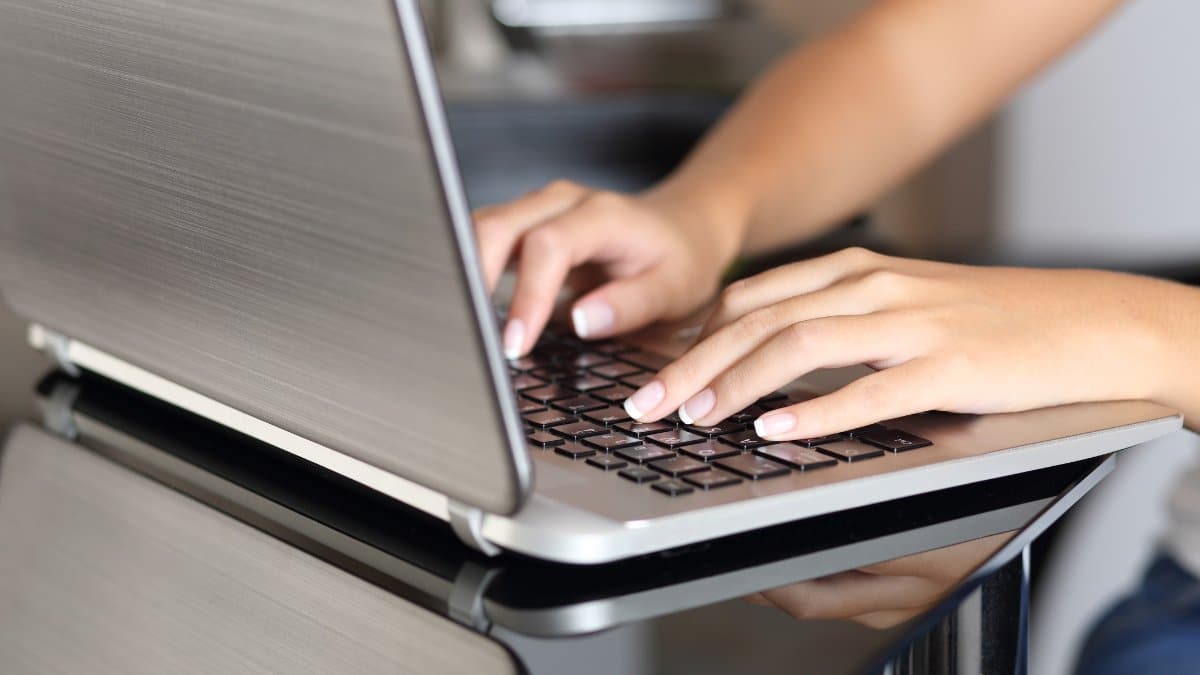 Close up of a woman hands typing in a laptop working at home in the kitchen table