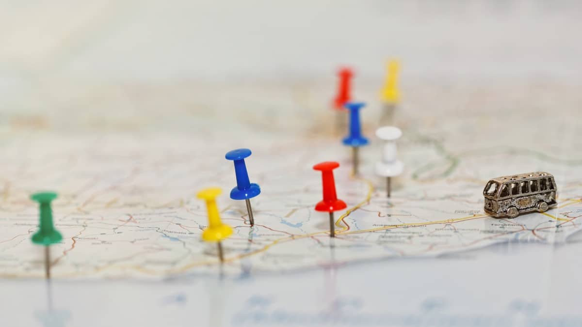 Vacation travel by coach concept. Map with road network and with pushpins marking country highlights and tourist attractions and a tiny toy coach on the road.