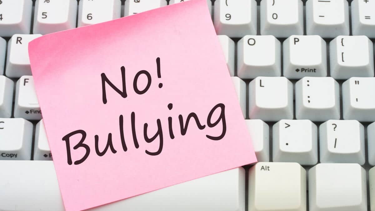 A computer keyboard with a sticky note saying no bulling, Stop internet bullying