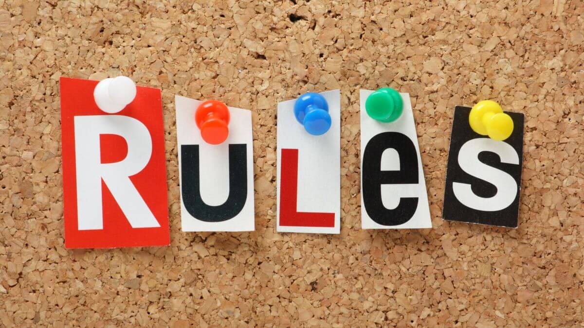 The word Rules n cut out magazine letters pinned to a cork notice board