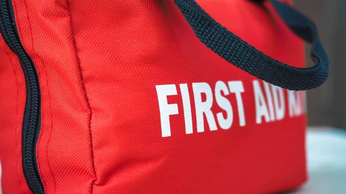 A red first aid kit bag with a black zip and handle, in closeup.