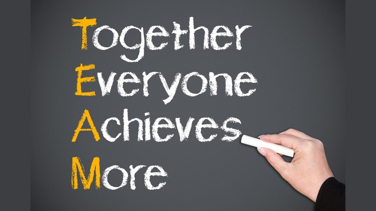 Hand of person writing together everyone achieves more on blackboard, teamwork concept.