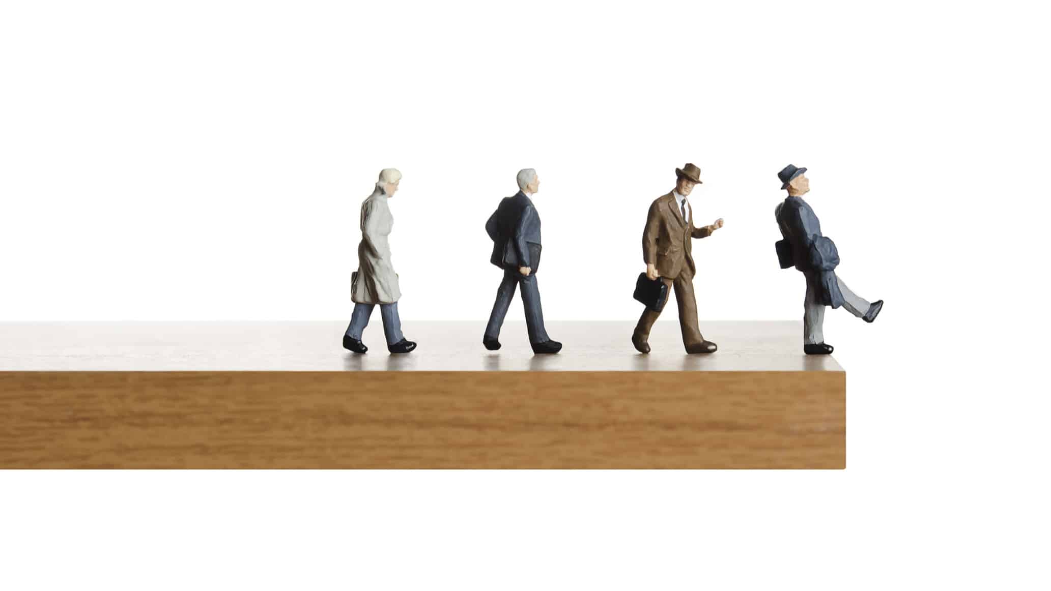 Walking off the edge. Business figurines walking off a ledge