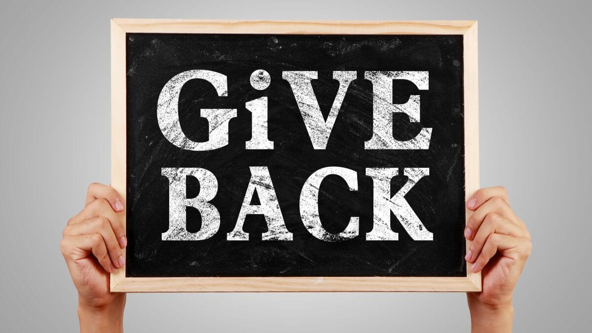 Person holding a sign that says "Give Back"