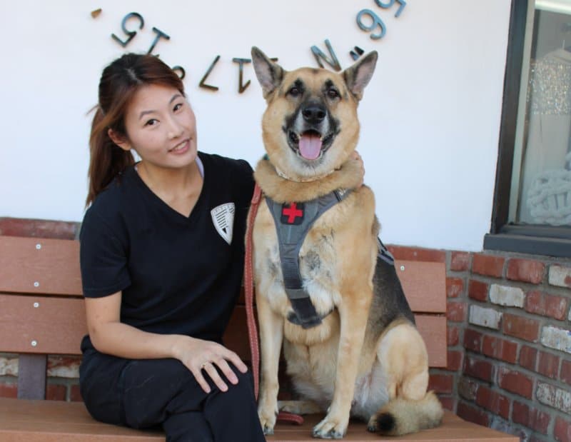 Asia Duhamel sitting on a bench with her Service Dog, German Shepherd known as "Lotus."