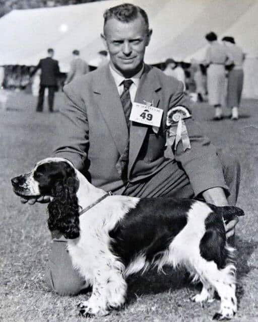 Old black and white photo of an English Cocker Spaniel and its handler at a dog show.