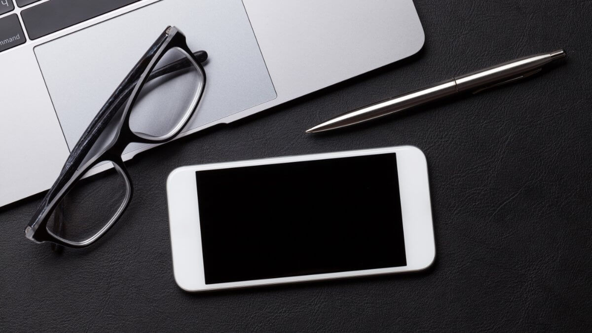 Office workplace table with supplies, smartphone and laptop.