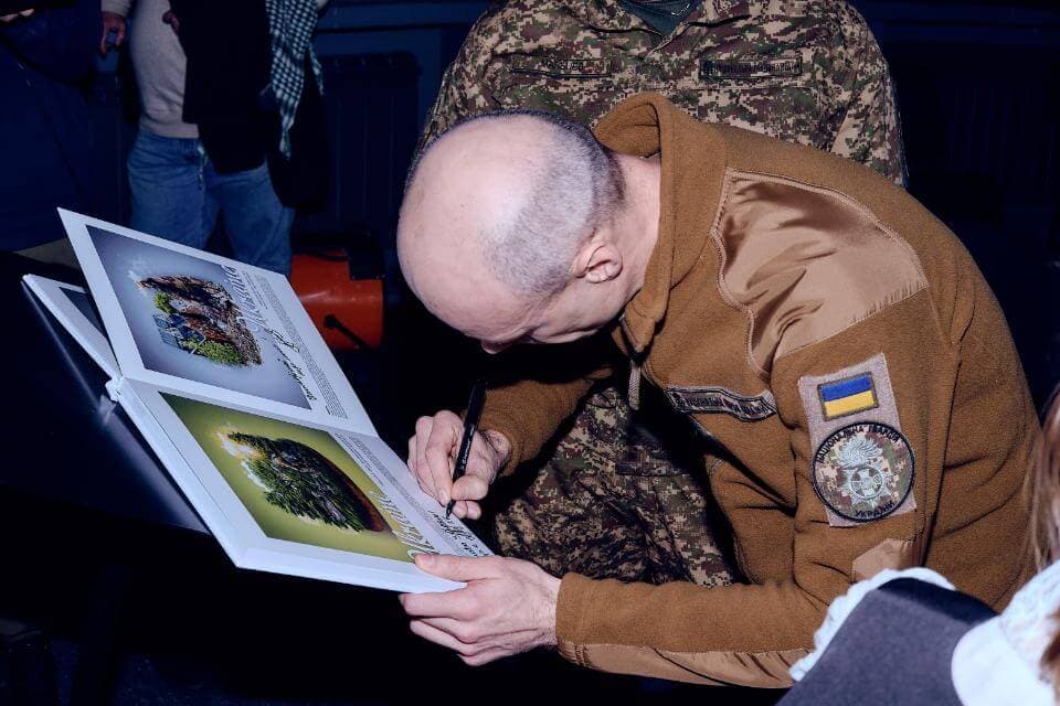 A hero’s owner from the National Guard of Ukraine signs the book,Dog-Hero of Ukraine . photo by Oleg Chechil, Ukraine