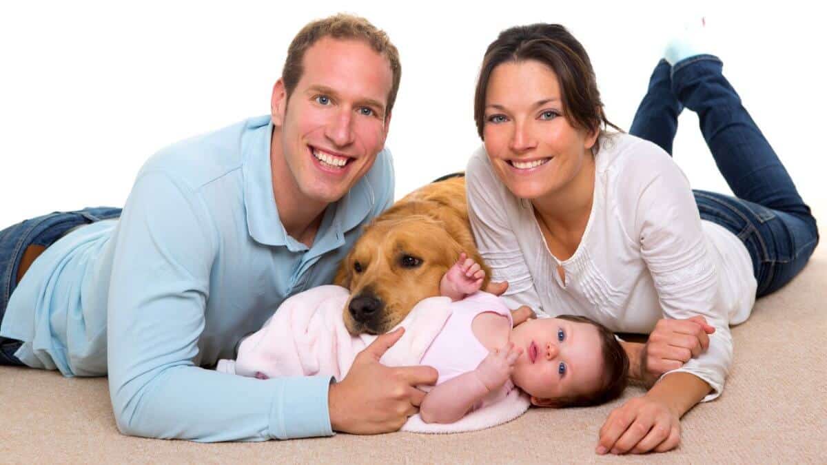 Baby, mother, and father. Happy family with Golden Retriever dog on carpet