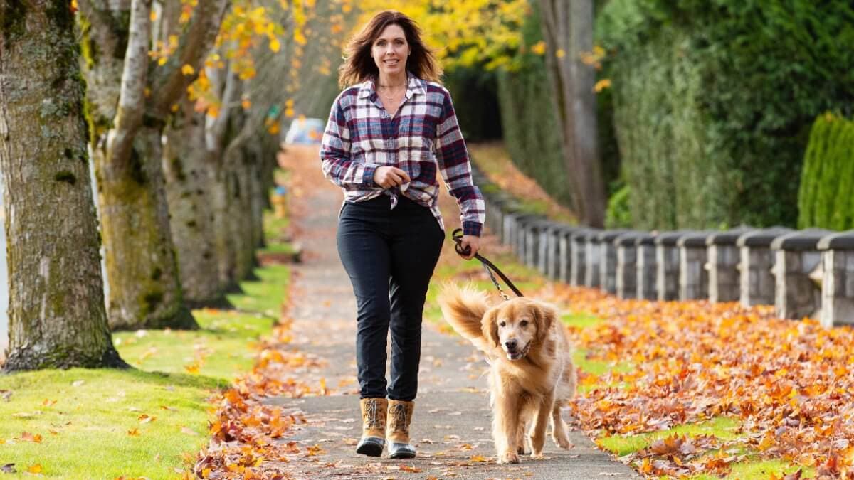 Woman walking a Golden Retriever dog in autumn