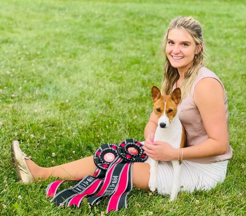 Professional Handler Ciara Cassell sitting on grass with her Basenji dog