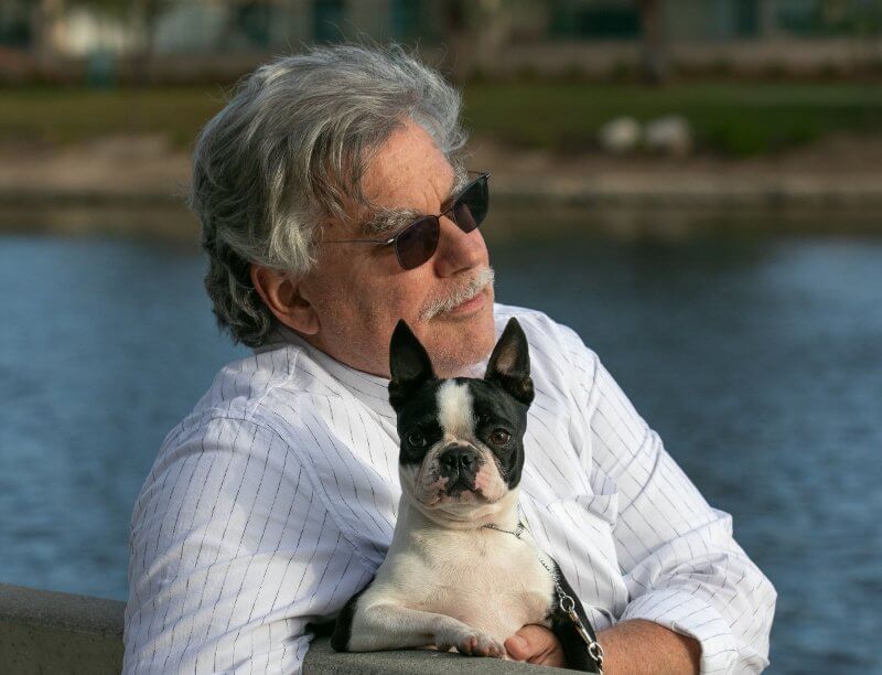 Owner Handler John Flora sitting with his Boston Terrier dog