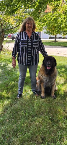 Carol Scerba with her dog, standing on the grass.
