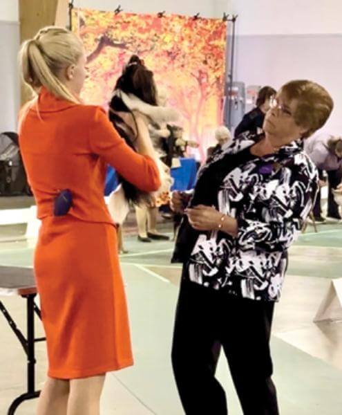 Two women standing next to each other at a dog show.