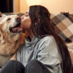 Woman is with Golden Retriever at home. Kissing the dog.