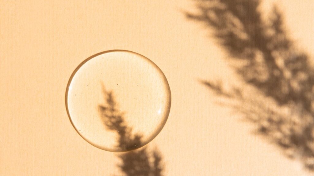 Transparent peptide gel on a beige background with an abstract shadow from a plant.