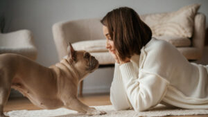 View from the side, lying down on the floor. Young woman is with her pug dog at home