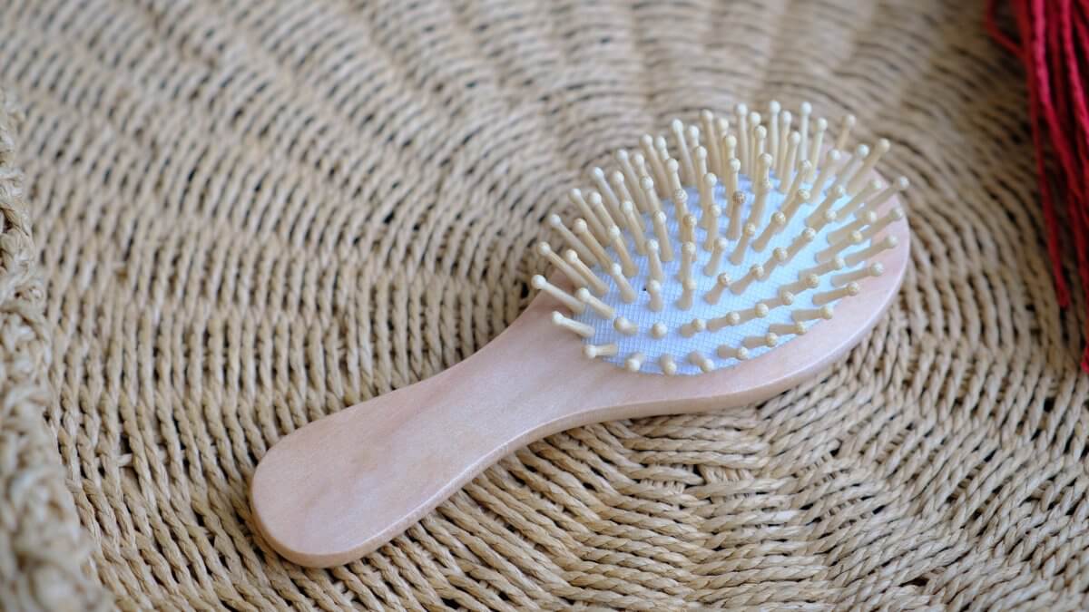 Small round wooden natural hair comb against the background of a wicker basket.