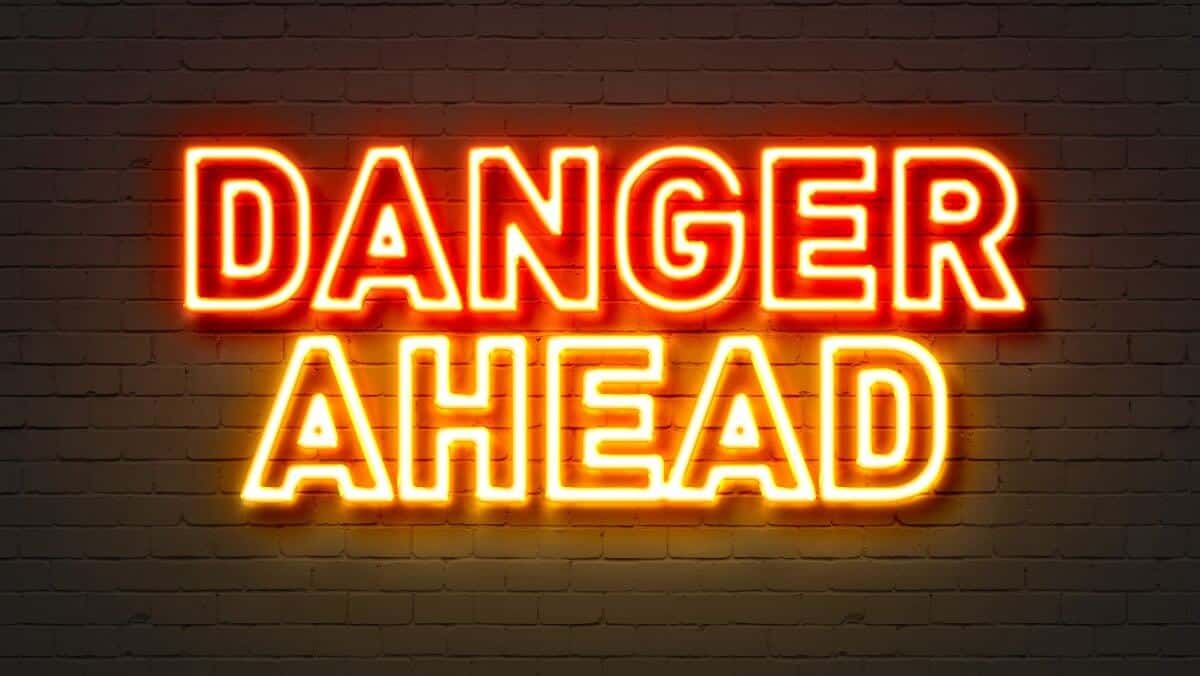 Danger ahead neon sign on brick wall background.