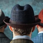 Three men wearing hats standing backwards looking in same direction.