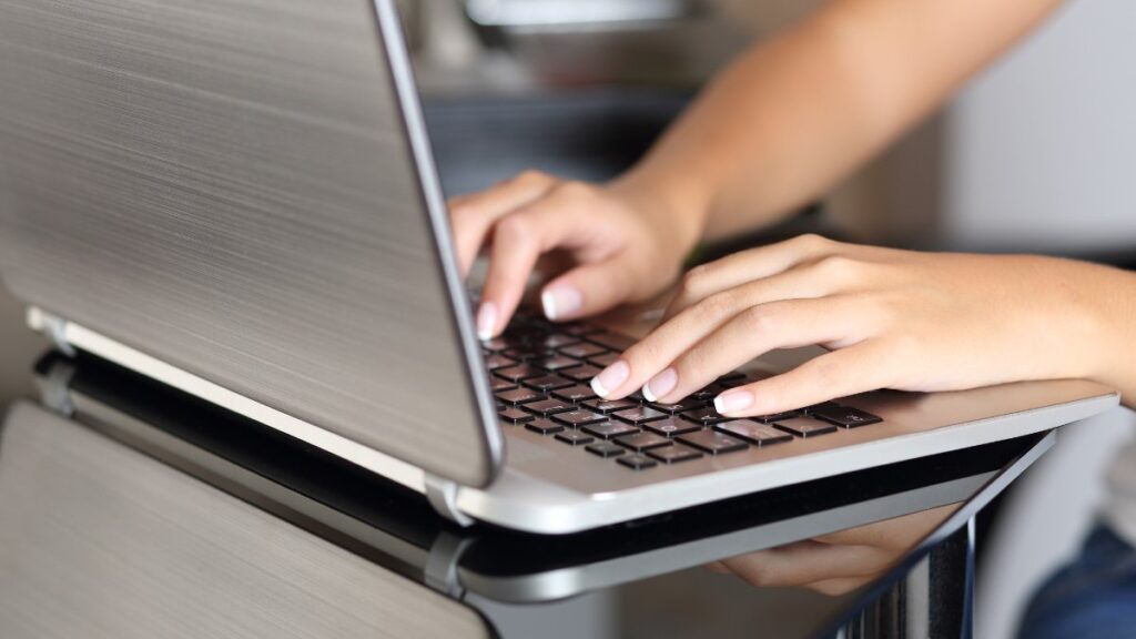 Close up of a woman hands typing in a laptop working at home in the kitchen table