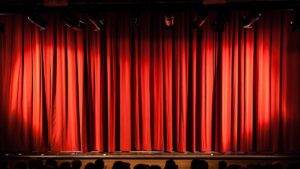 A closed red stage curtain in a small theater