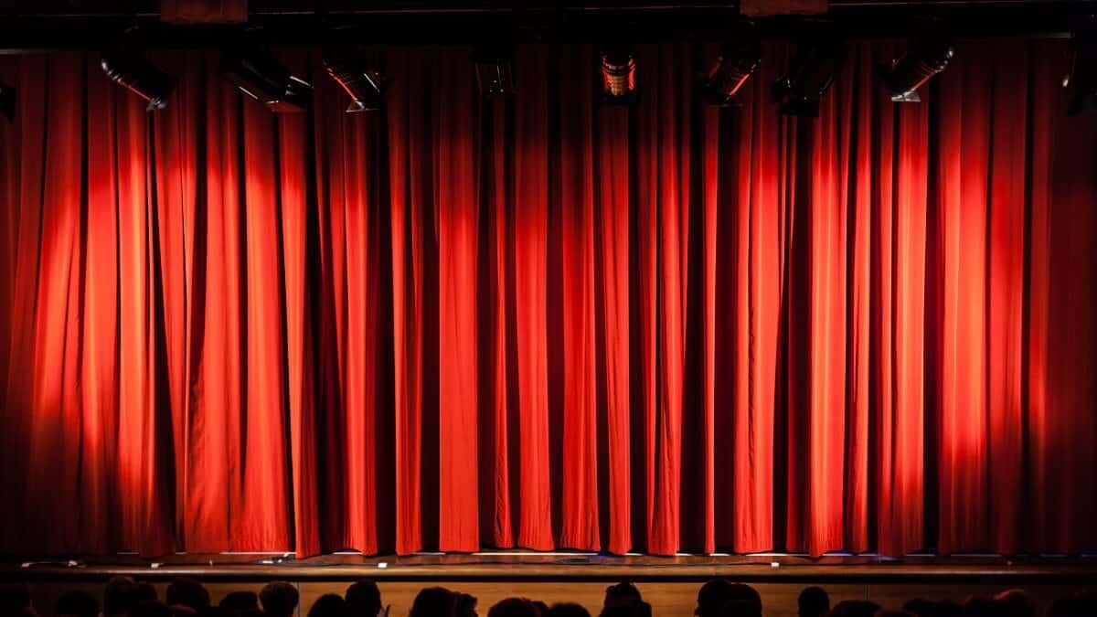 A closed red stage curtain in a small theater