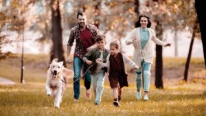 smiling family with a Labrador running on meadow in autumn-park