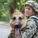 Man in military uniform with German shepherd dog, outdoors