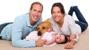 Baby, mother, and father. Happy family with Golden Retriever dog on carpet