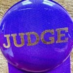 Purple badge with a Judge written on it