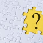 Question mark on jigsaw puzzle with yellow background.