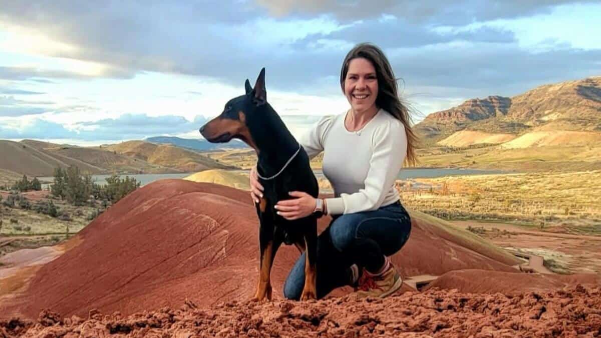 Cheyenne Calvert with a Doberman Pinscher on a hill