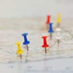 Vacation travel by coach concept. Map with road network and with pushpins marking country highlights and tourist attractions and a tiny toy coach on the road.