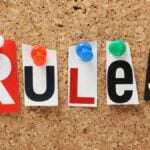 The word Rules n cut out magazine letters pinned to a cork notice board