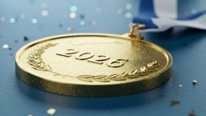 Close up of glittering 2026 championship gold medal. This macro shot captures a finely textured gold medal embossed with the year 2026 and a classic laurel wreath design.