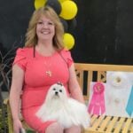 Melissa Robison sitting on a bench with a white Maltese dog.