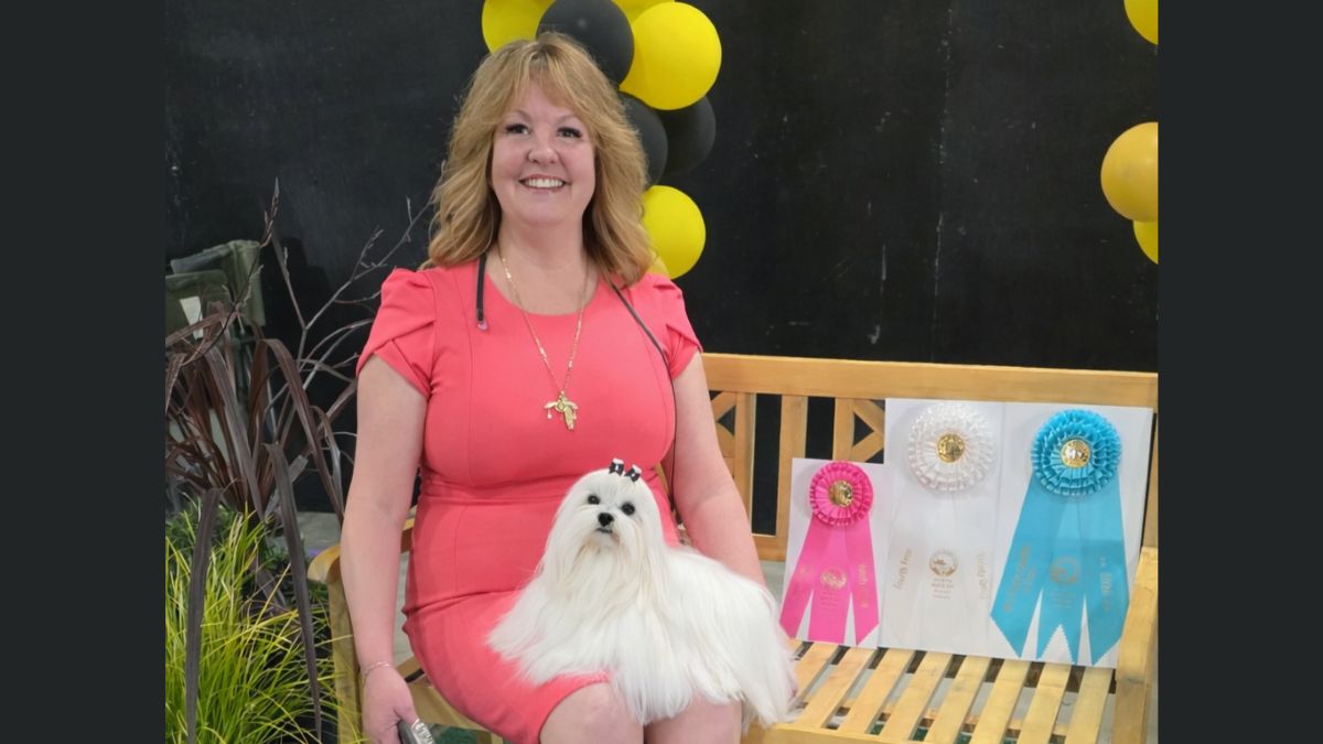 Melissa Robison sitting on a bench with a white Maltese dog.