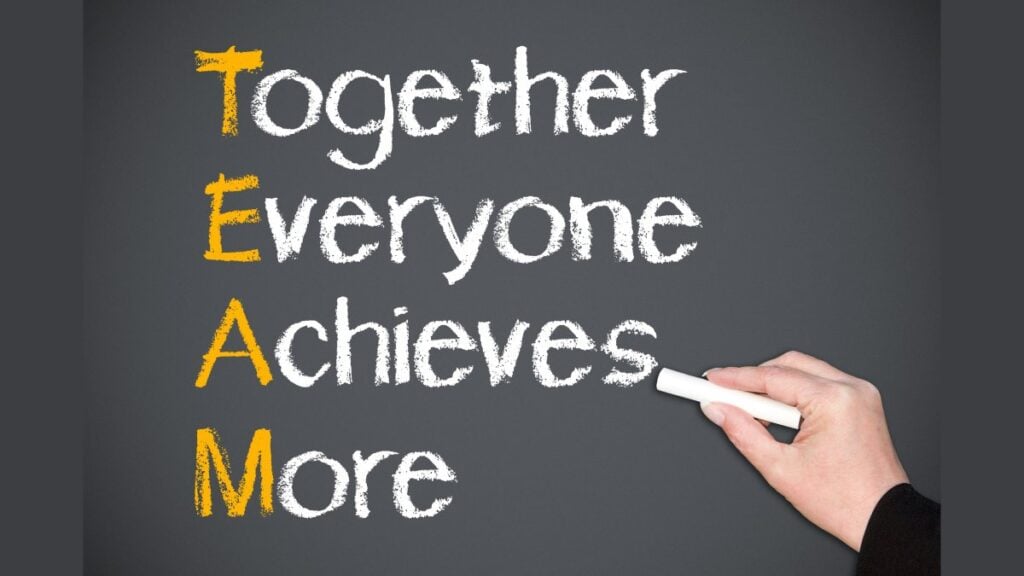 Hand of person writing together everyone achieves more on blackboard, teamwork concept.