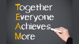 Hand of person writing together everyone achieves more on blackboard, teamwork concept.