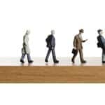Walking off the edge. Business figurines walking off a ledge