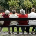 Senior ladies at the park. 4 old friends sitting on a park bench enjoying some friendly conversation